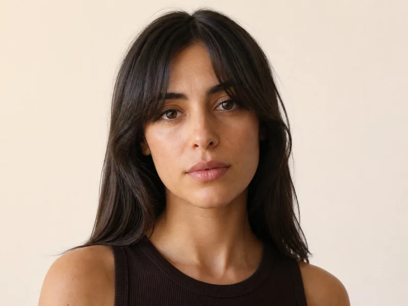 A woman with soft curtain bangs falling either side of her forehead