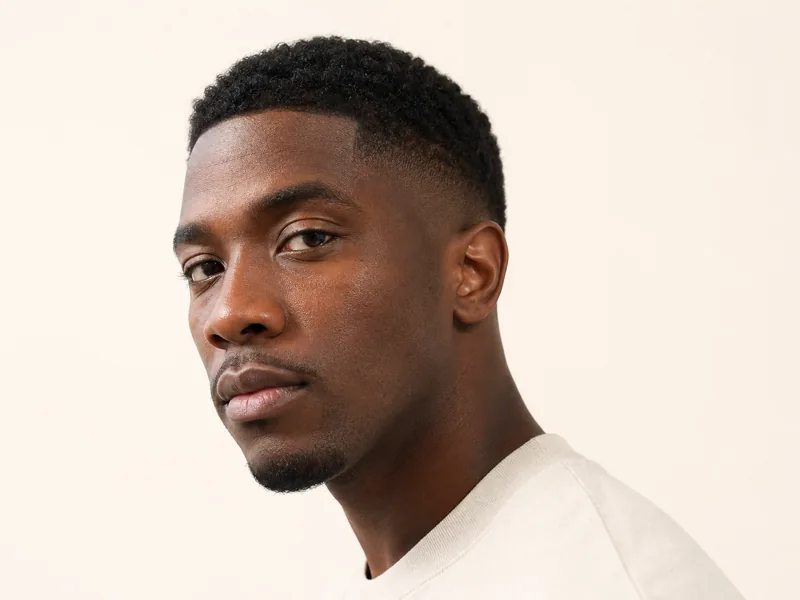 A man with a fresh mid taper fade seen from a three-quarter angle